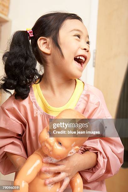 a young girl giving her doll a bath. - chinese dolls stock pictures, royalty-free photos & images