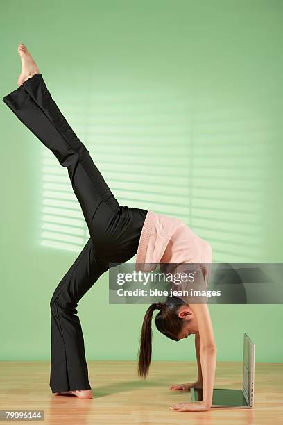 a businesswoman doing body exercise and seeing laptop screen upside down. - businesswoman handstand stock pictures, royalty-free photos & images