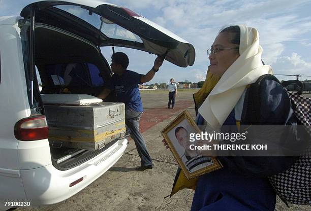 Catholic nun holds a portrait of the late Catholic priest Father Reynaldo Roda shortly his casket after arrived at Edwin Andrews airbase in Zamboanga...