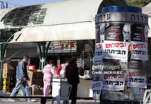 Israelis walk past posters against Israeli Prime Minister Ehud Olmert in the southern Israeli city of Sderot, 18 January 2007. At least five rockets...