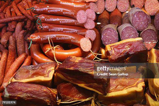 Different types of traditional German sausage, ham, salami and other meat products lie on display at a butcher's stand at the Gruene Woche...