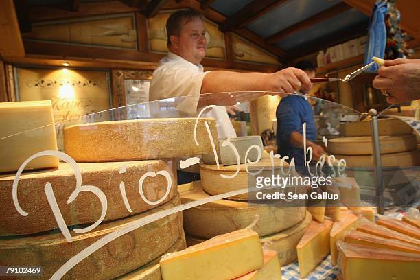 Worker offers a visitor a sample of organic mountain cheese at a stand at the Gruene Woche agricultural trade fair January 18, 2008 in Berlin,...