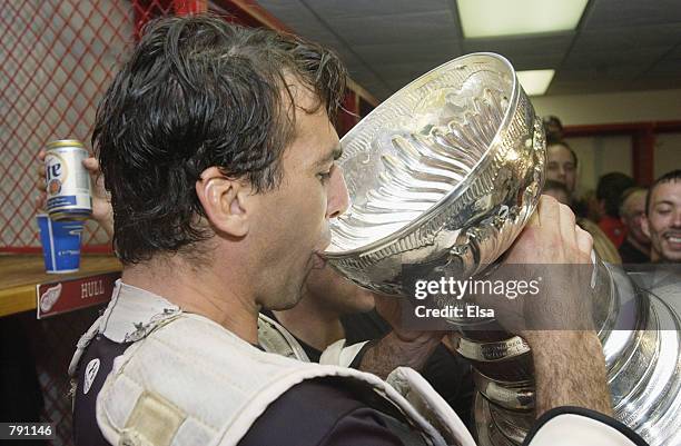 Chris Chelios of the Detroit Red Wings drinks champagne from the Stanley Cup in the locker-room after eliminating the Carolina Hurricanes during game...