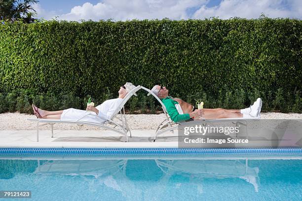 par relajante junto a la piscina - recostarse fotografías e imágenes de stock