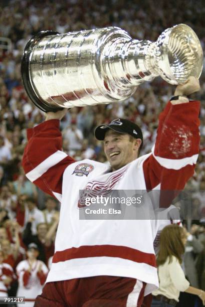 Goaltender Dominik Hasek of the Detroit Red Wings raises the Stanley Cup after eliminating the Carolina Hurricanes during game five of the NHL...