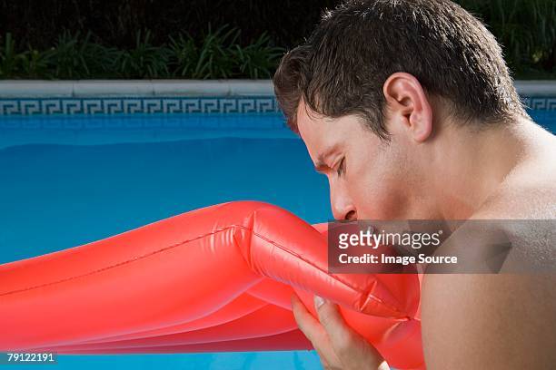 man blowing into inflatable mattress - inflate stockfoto's en -beelden