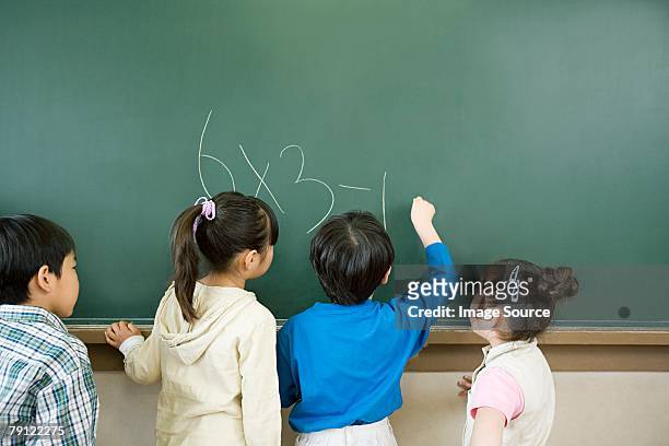 a boy writing a sum on a blackboard - child writing on chalkboard stock pictures, royalty-free photos & images