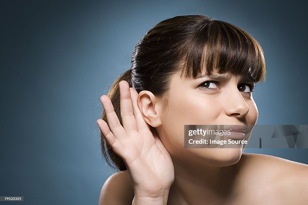Woman putting hand to her ear