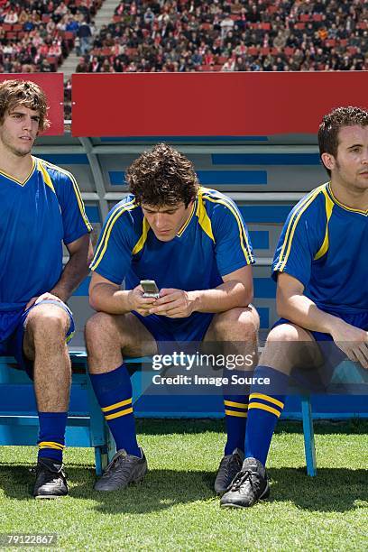 footballer using cell phone - soccer bench stock pictures, royalty-free photos & images