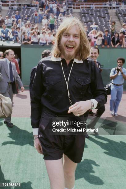 English composer and keyboard player Rick Wakeman pictured wearing referee kit of black shirt and shorts at a sport's stadium in the United States...