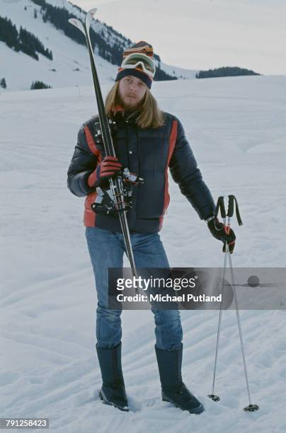 English composer and keyboard player Rick Wakeman pictured in ski attire holding a pair of skis on the snow covered slopes in Switzerland on 16th...