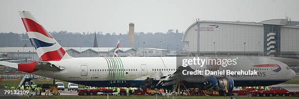 Emergency crew install a low loader under the body of the Boeing 777 plane which crashed on Thursday, in preparation to move it from Heathrow's south...