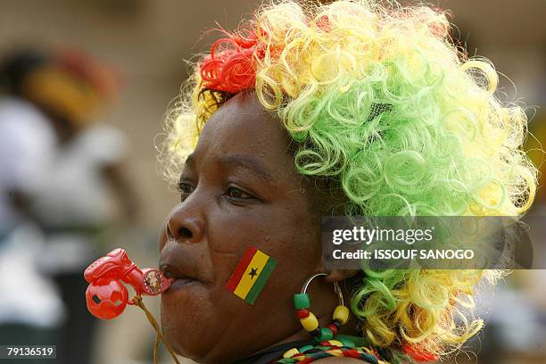 Wearing a wig with the colour of the national flag, a supporter of the "Black stars" the national team of football of Ghana follows on a big screen...