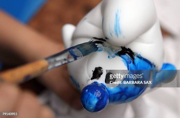 Child paints the figurine of a smurf during an event 21 January 2008 in Berlin to celebrate the smurfs' 50th anniversary. The smurfs were invented by...