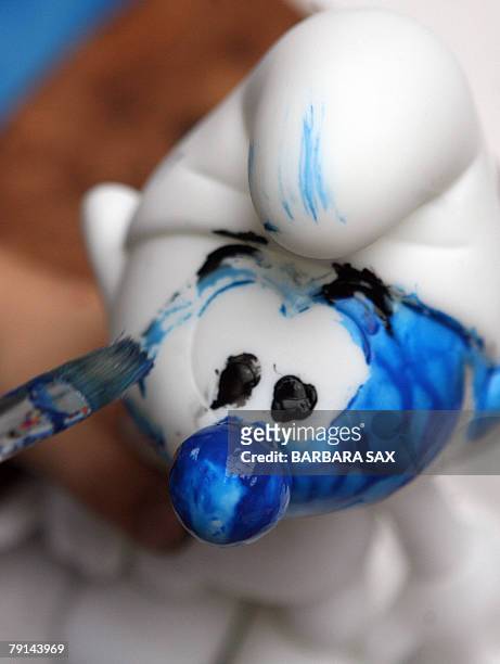 Child paints the figurine of a smurf during an event 21 January 2008 in Berlin to celebrate the smurfs' 50th anniversary. The smurfs were invented by...