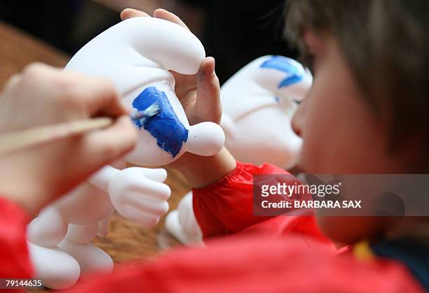 Children paint figurines of smurfs during an event 21 January 2008 in Berlin to celebrate the smurfs' 50th anniversary. The smurfs were invented by...