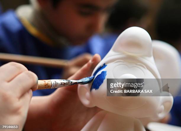 Children paint figurines of smurfs during an event 21 January 2008 in Berlin to celebrate the smurfs' 50th anniversary. The smurfs were invented by...