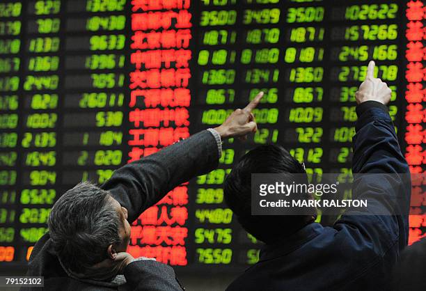 Chinese investors watch a stock price board showing the green colouring which indicates falling prices at a private securities firm in Shanghai, 22...