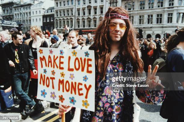 Man dressed as a hippy with a placard reading 'Make Love Not Money' at a Reclaim The Streets demonstration in London, 1st May 2000.