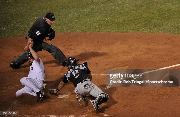 Kevin Youkilis of the Boston Red Sox slides safely into home before the tag of Yorvit Torrealba of the Colorado Rockies as umpire Ed Montague looks...
