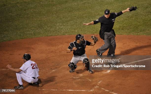 Kevin Youkilis of the Boston Red Sox slides safely into home before the tag of Yorvit Torrealba of the Colorado Rockies as umpire Ed Montague signals...