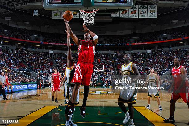 Tracy McGrady of the Houston Rockets goes to the basket between the defense of Damien Wilkins and Johan Petro of the Seattle SuperSonics on January...