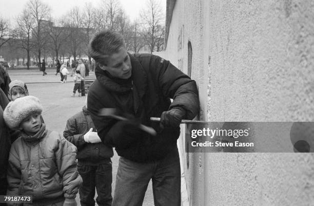 An East Berliner chips away at a section of the Berlin Wall at the effective end of the city's partition, 31st December 1989.