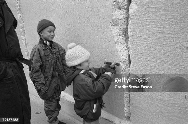 An East German boy chips away at a section of the Berlin Wall at the effective end of the city's partition, 31st December 1989.