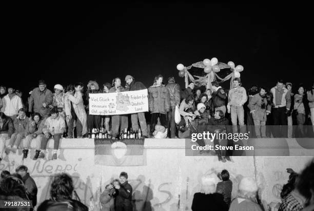 View from the east of Berliners gathered on the Berlin Wall to celebrate the New Year and the effective end of the city's partition, 31st December...