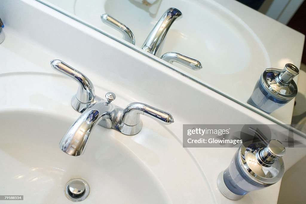 Close-up of a faucet and a soap dispenser on a bathroom sink