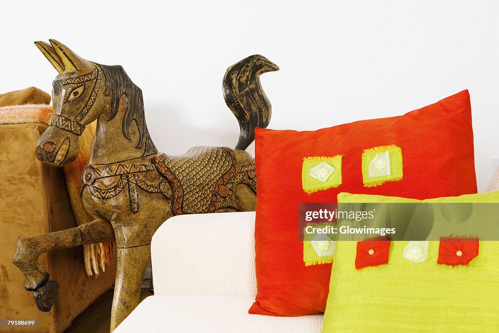 Close-up of cushions on a couch with a wooden horse