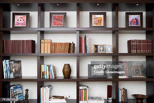 books and picture frames in shelves - bookshelf foto e immagini stock