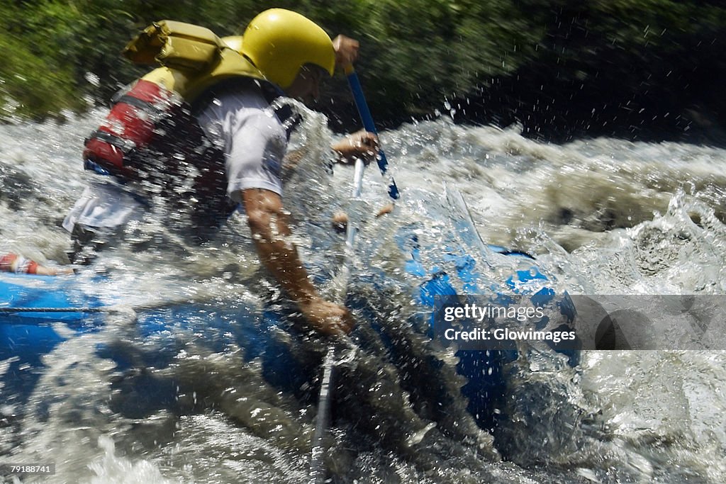 Side profile of two people rafting in a river