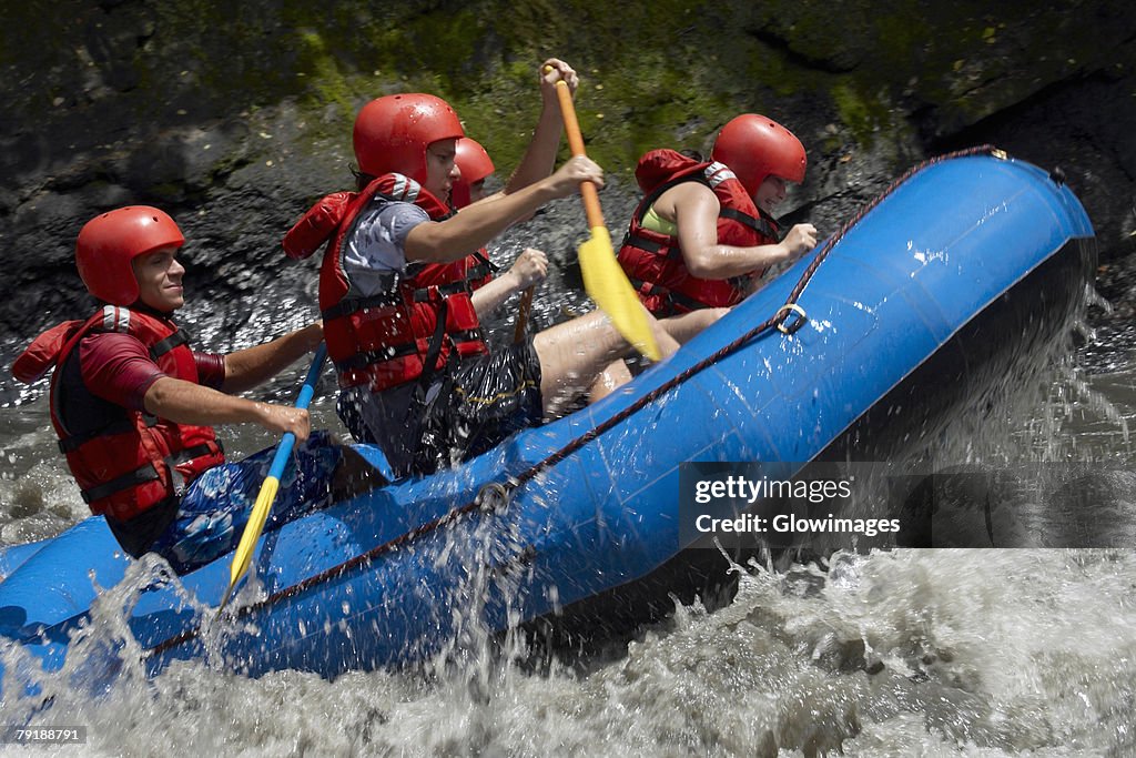 Side profile of five people rafting in a river