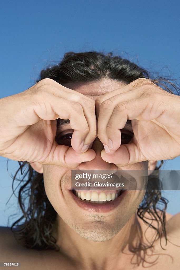 Close-up of a mid adult man making circles around his eyes with fingers