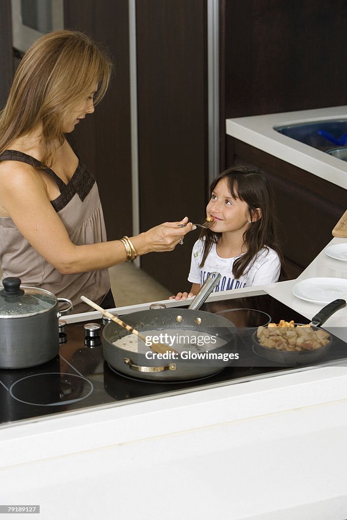 Mature woman feeding her daughter in a kitchen