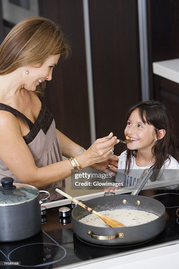 Side profile of a mature woman feeding food to her daughter