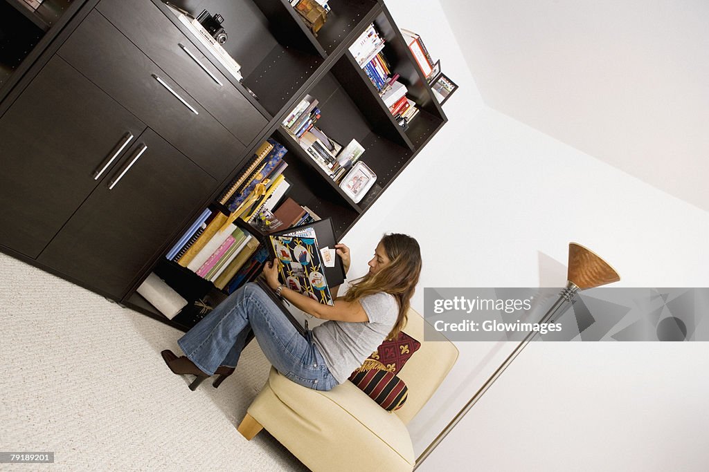 Mid adult woman sitting on a couch and reading a magazine