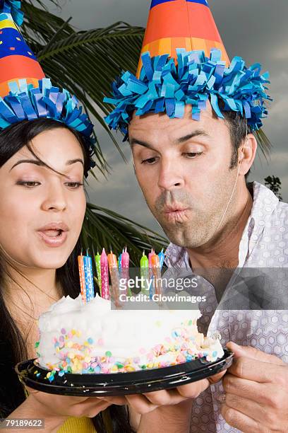 close-up of a young woman with a mid adult man blowing candles on a birthday cake - holding birthday cake stock pictures, royalty-free photos & images