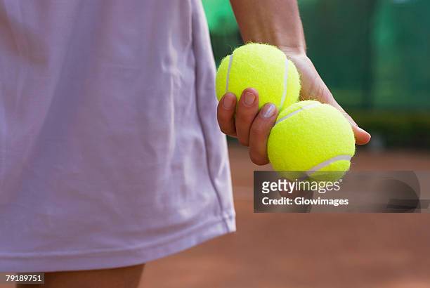 mid section view of a young woman holding two tennis balls in her hand - tennis ball hand stock pictures, royalty-free photos & images