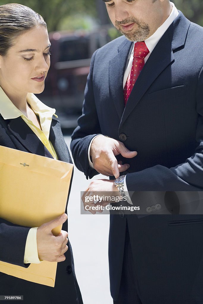 Businessman and a businesswoman checking the time in a wristwatch