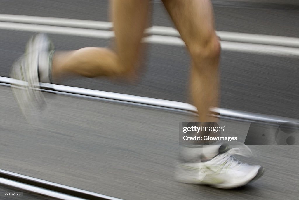 Low section view of a male athlete running on a running track