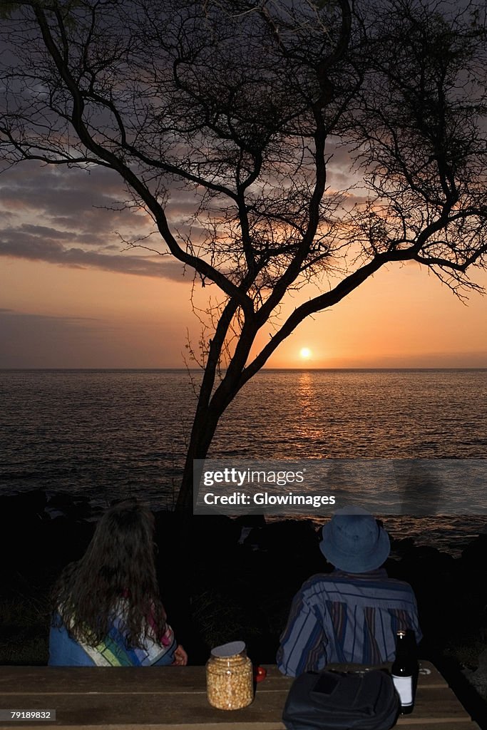 Man and a woman looking at sunset over the sea, Pakini Nui Wind Project, South Point, Big Island, Hawaii Islands, USA