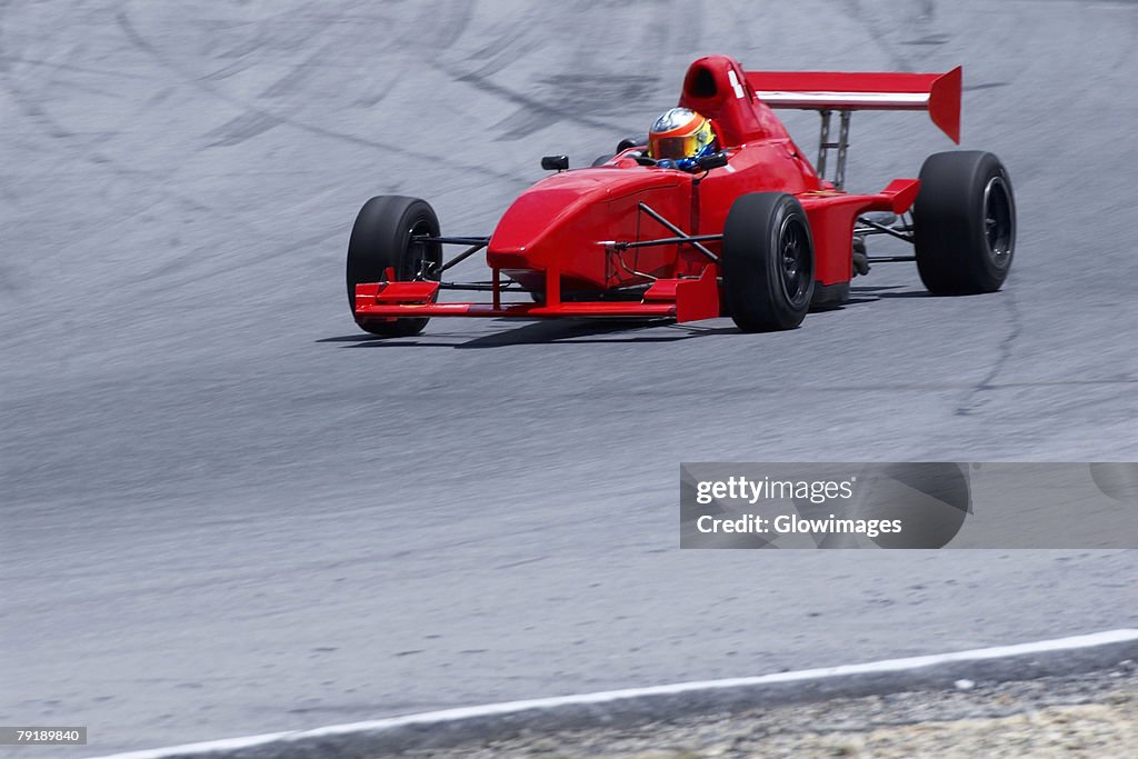 Person driving a open-wheel single-seater racing car racing car on a motor racing track