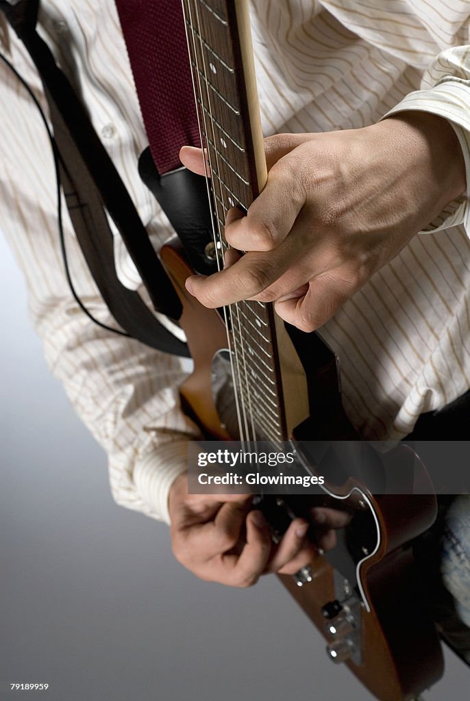 Mid section view of a male guitarist playing a guitar