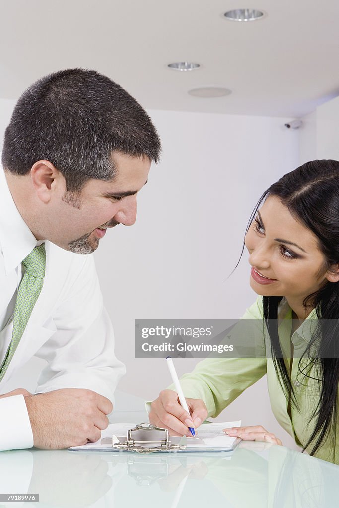 Businesswoman talking to a businessman while writing