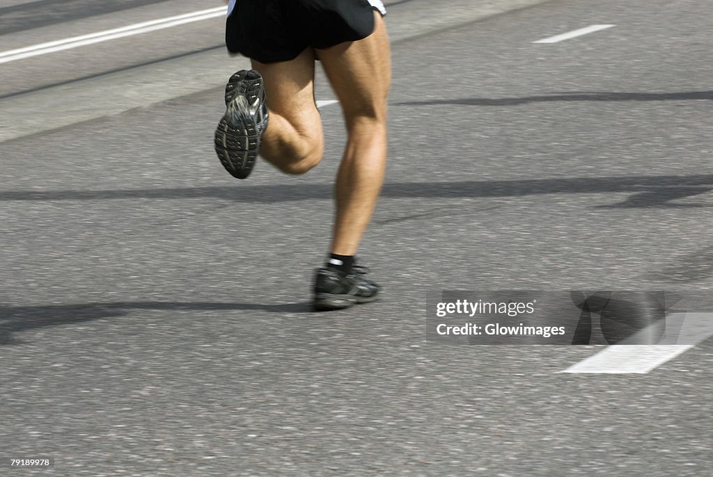 Low section view of a male athlete running on a running track