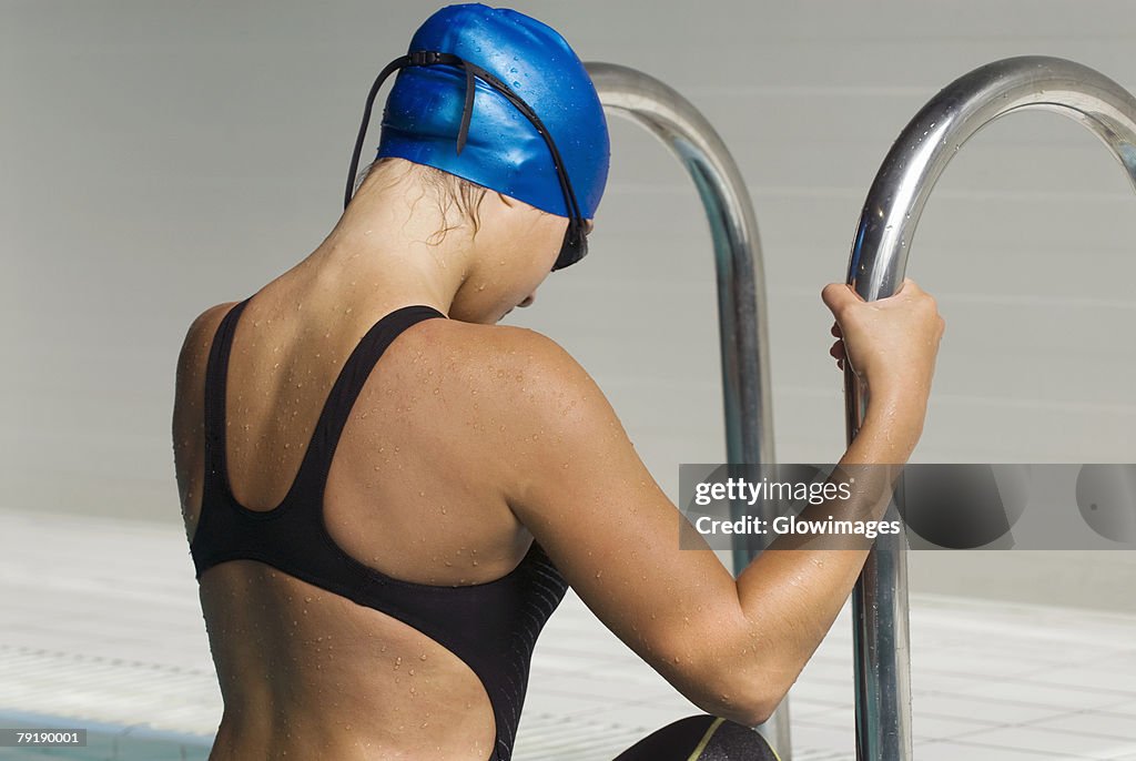 Side profile of a teenage girl stepping out from a swimming pool