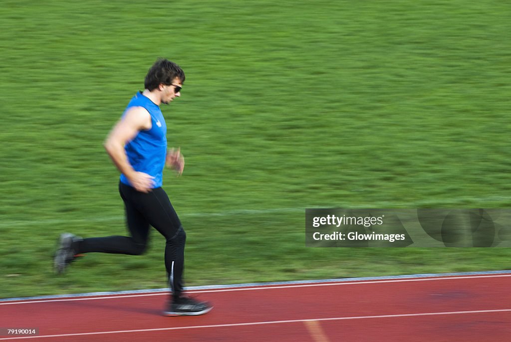Side profile of a mid adult man running on a sports track
