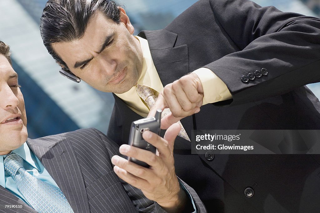 Close-up of two businessmen using a palmtop